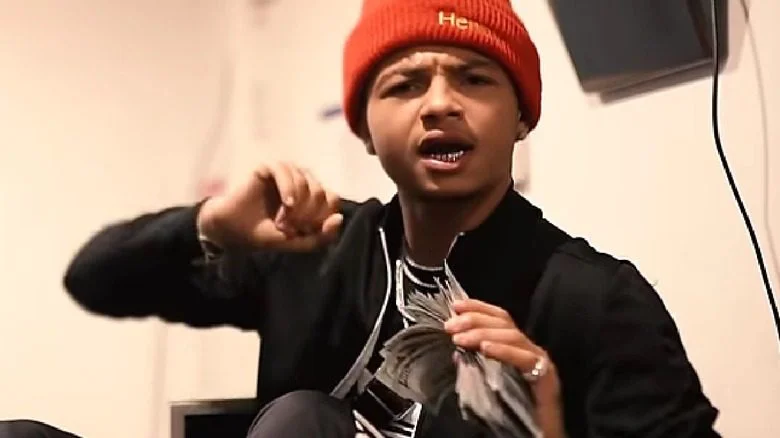 Lul G assis tenant une liasse de billets