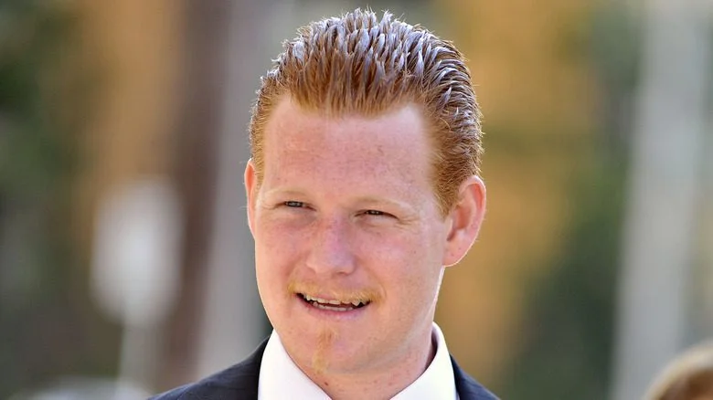 Redmond O'Neal souriant à l'extérieur dans un costume