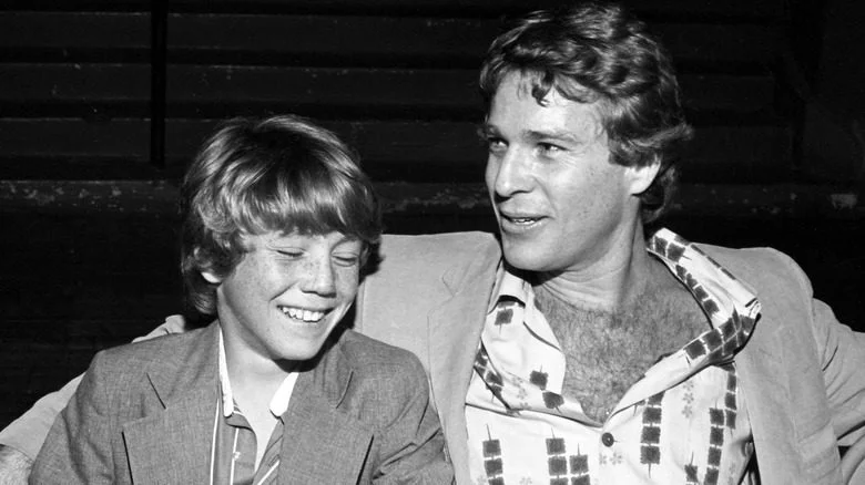 Ryan O'Neal et le jeune Griffin O'Neal assis en souriant