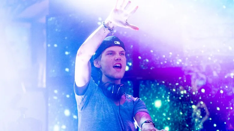 Avicii sur scène, casquette de baseball, main levée