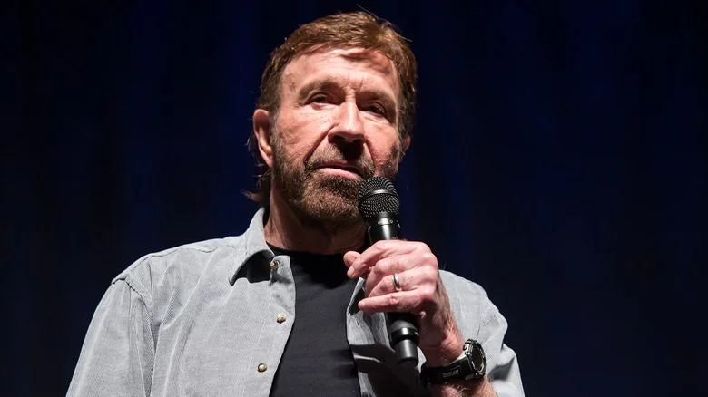Chuck Norris tenant un microphone sur un fond noir