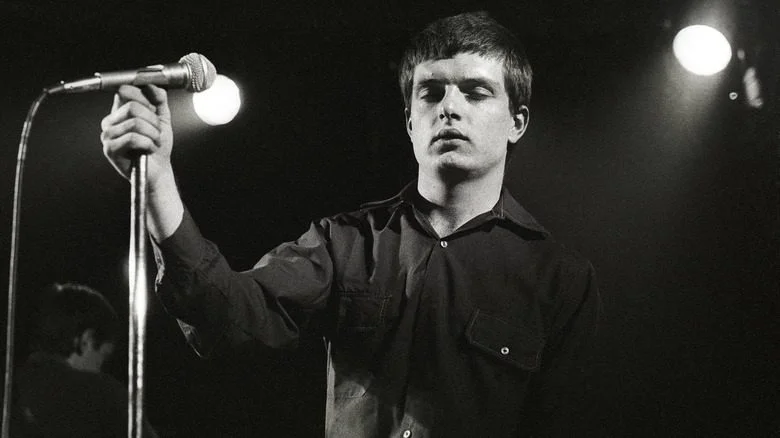 Ian Curtis tenant un pied de micro