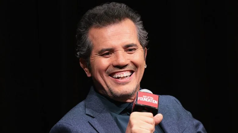 John Leguizamo souriant tenant un micro