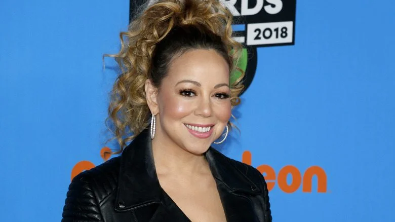 Mariah Carey souriante en veste noire à un événement