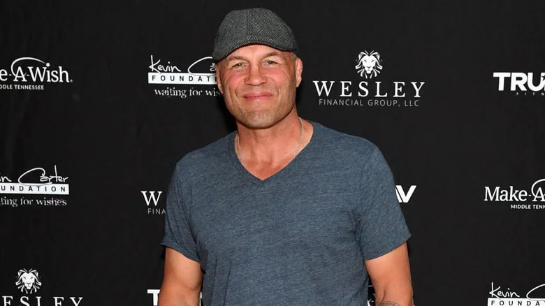 Randy Couture en t-shirt gris et casquette à un événement