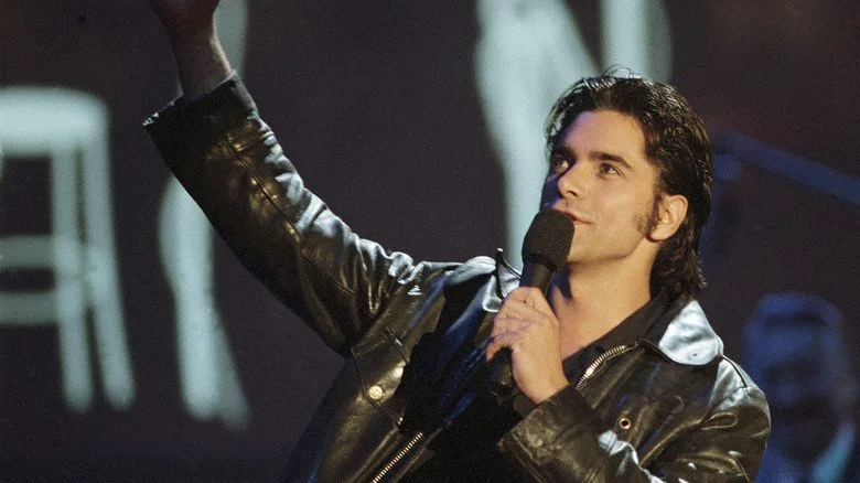 John Stamos dans une veste en cuir noir avec un microphone