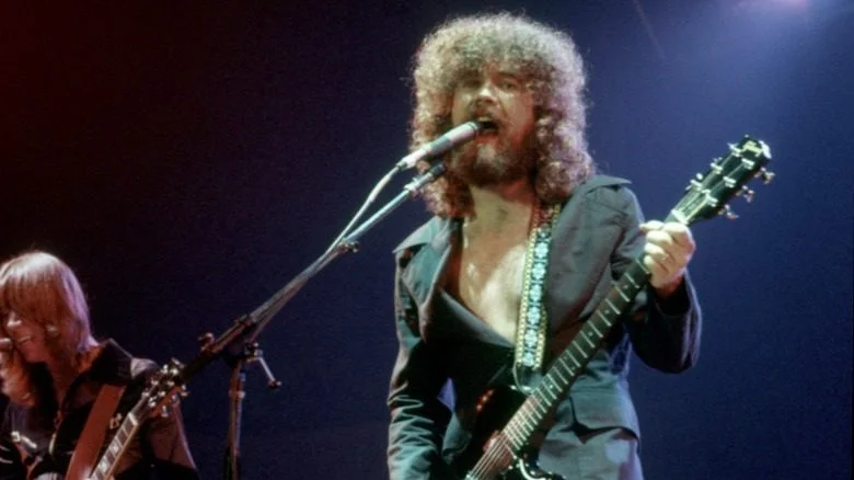 Brad Delp chantant et jouant de la guitare sur scène