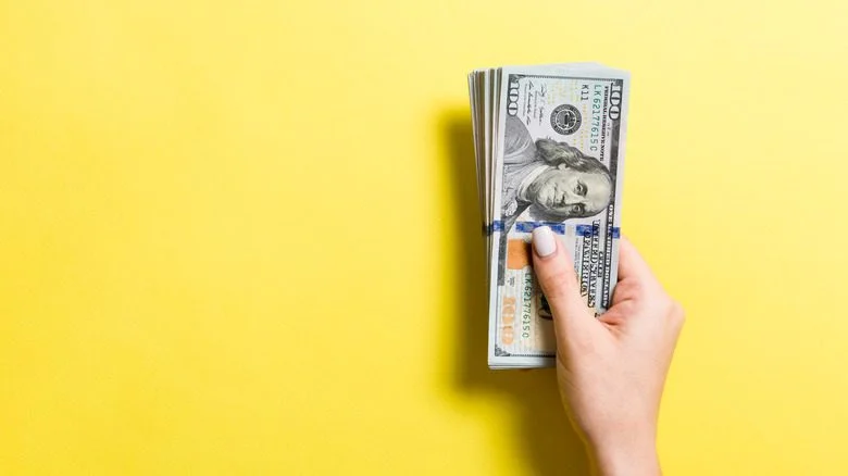 Main tenant des billets de cent dollars