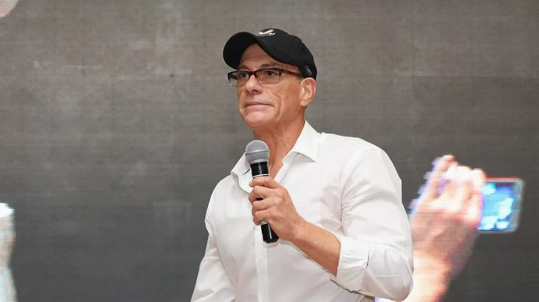 JCVD tenant un micro sur scène