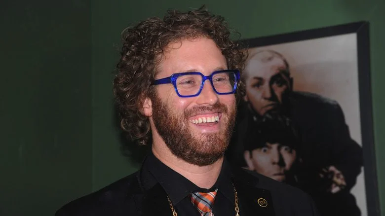 T.J. Miller avec des lunettes bleues souriant