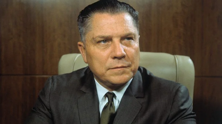 Jimmy Hoffa assis en costume gris et cravate