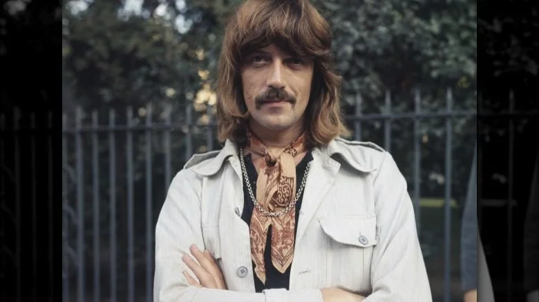 Jon Lord les bras croisés, souriant dans une veste blanche