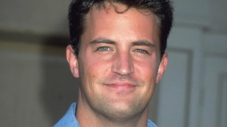 Matthew Perry en chemise bleue souriant