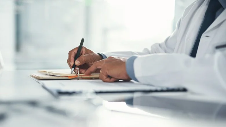 médecin écrivant sur un clipboard