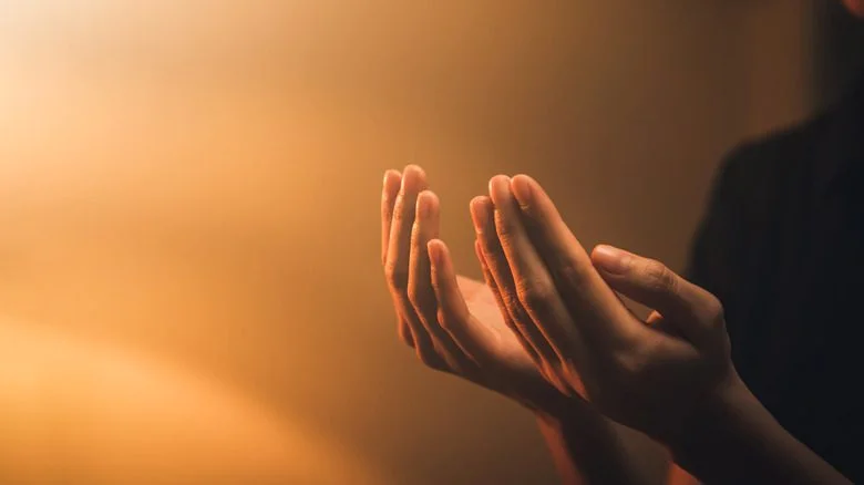 mains priant sous une lumière