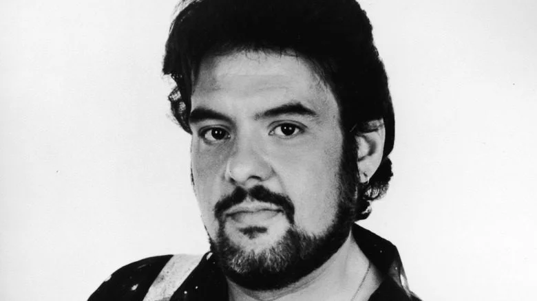 Robert Pastorelli avec une barbe, regard neutre sur fond blanc