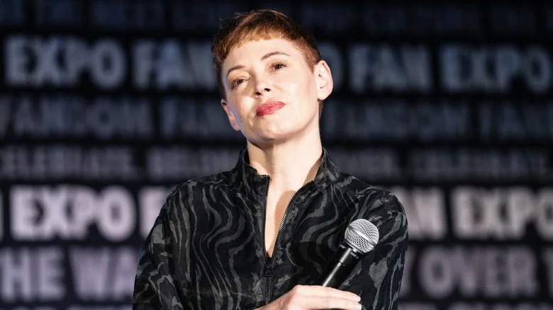 Rose McGowan microphone en main, bras croisés