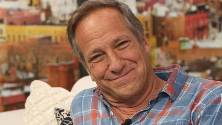 Mike Rowe s'appuyant sur un canapé, chemise à carreaux