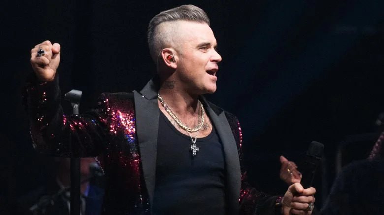 Robbie Williams holding a microphone onstage