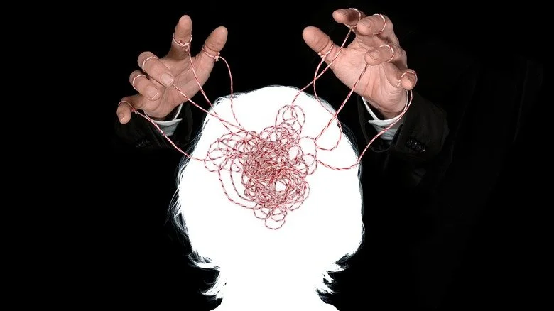 Hands holding tangle of string in a brain