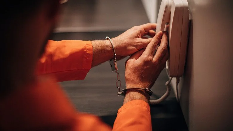 inmate menotté utilisant un téléphone