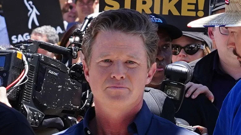 Billy Bush en chemise bleue au milieu de photographes