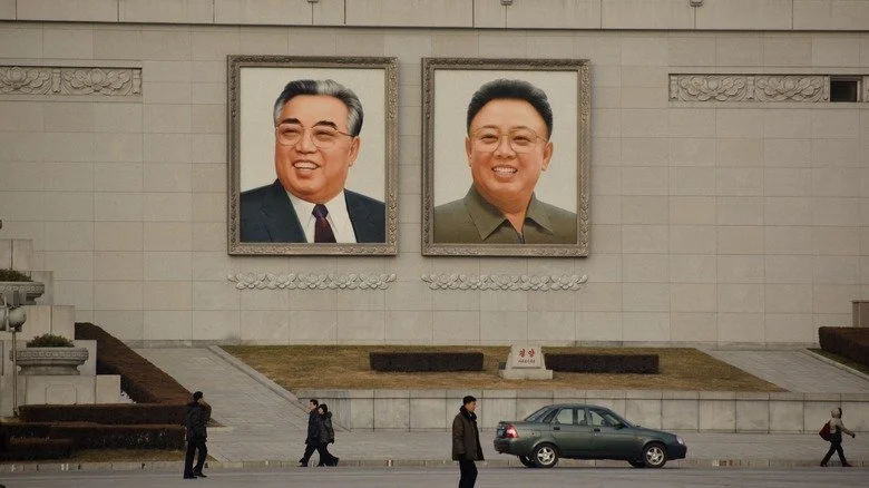 Des personnes passent devant des images de Kim Il-sung et Kim Jong-il