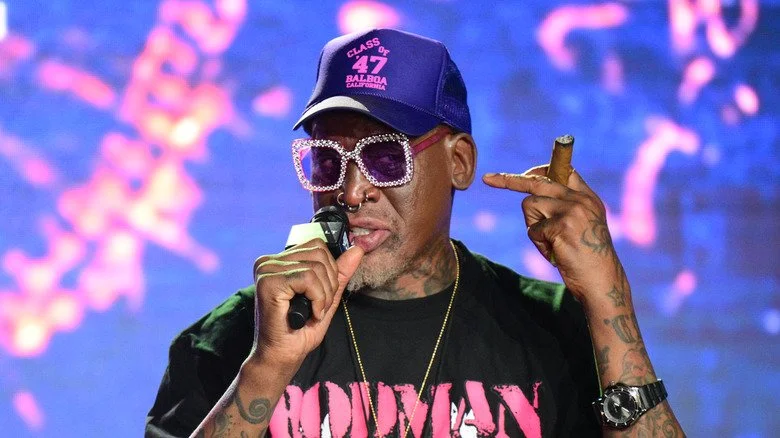 Dennis Rodman avec des lunettes de soleil parlant dans un micro lors d'un événement