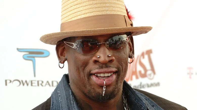 Dennis Rodman souriant avec chapeau et lunettes de soleil lors d'un événement