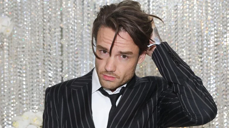 Liam Payne avec des cheveux en désordre devant un fond étincelant