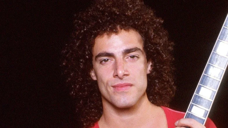 Neal Schon souriant tenant une guitare