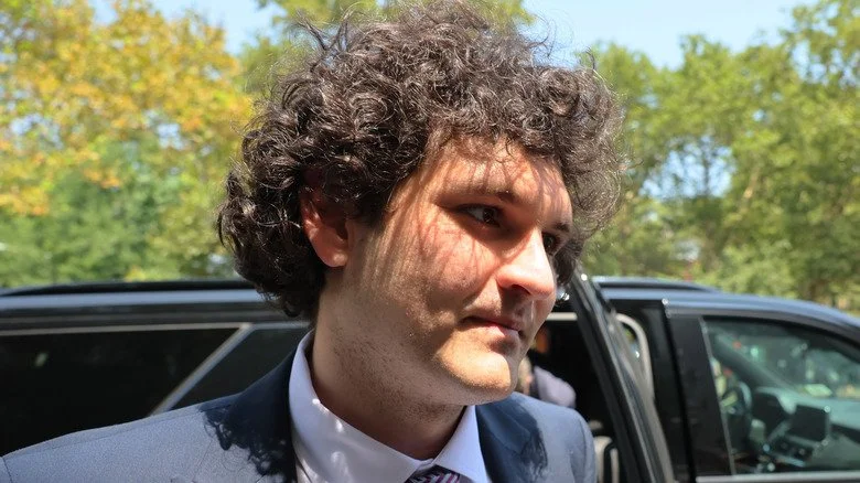 Sam Bankman-Fried en costume à côté d'une voiture