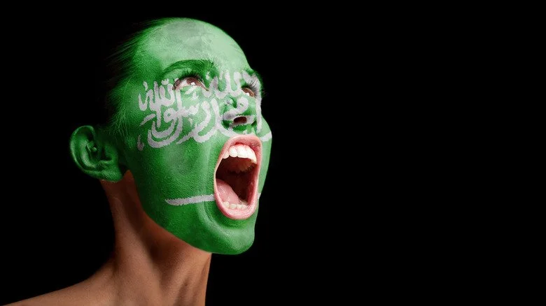 visage de femme peint aux couleurs du drapeau saoudien