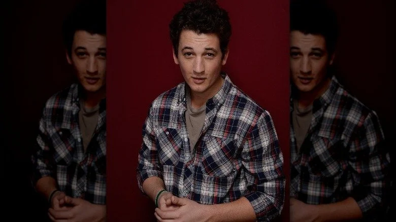 Miles Teller portant un flanelle et souriant