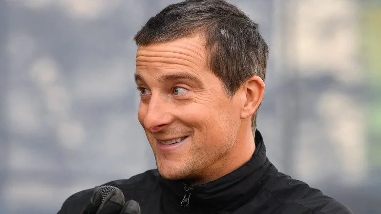 Bear Grylls souriant parmi les arbres