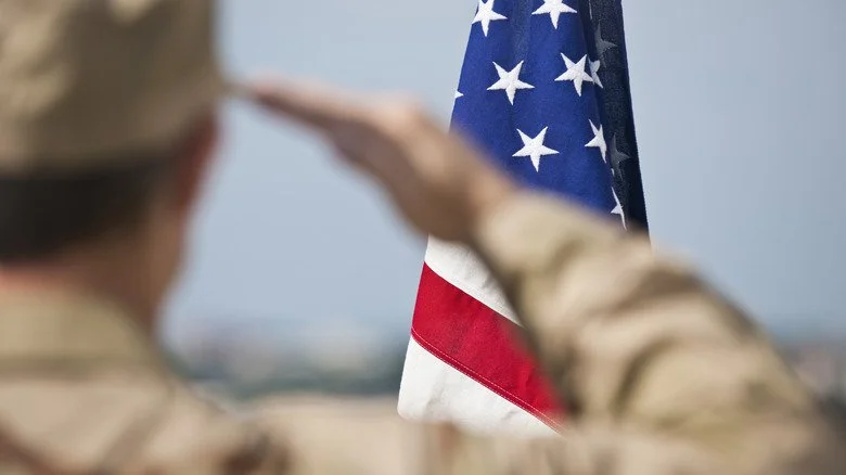 Un soldat en uniforme saluant le drapeau américain
