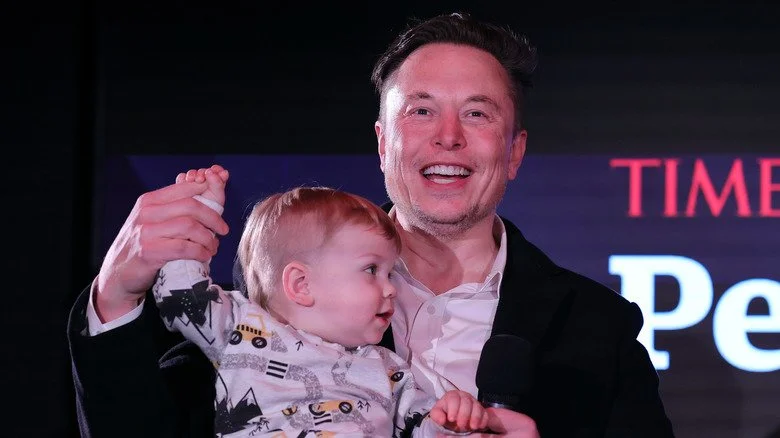 Elon Musk souriant avec un bébé