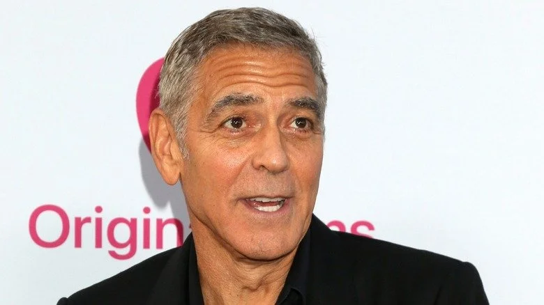 George Clooney souriant sur fond blanc lors d'un événement