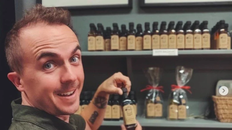 Frankie Muniz posant avec des bouteilles d'huile d'olive dans son magasin