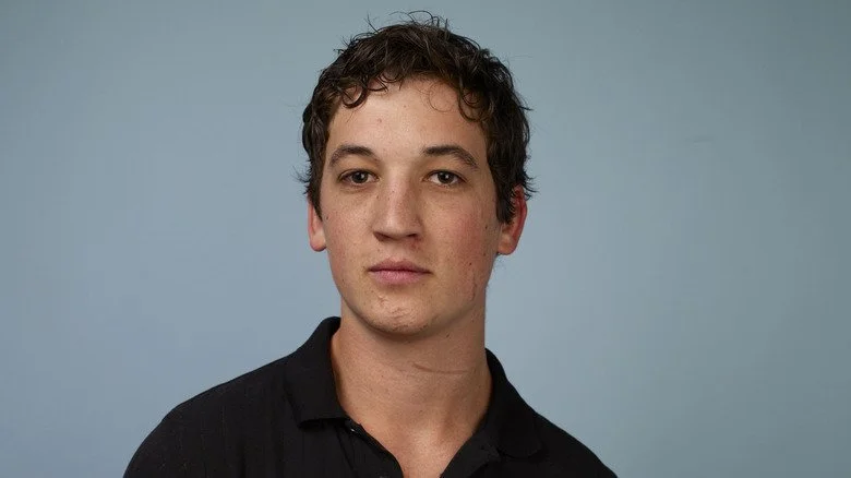 Miles Teller portant une chemise noire et posant