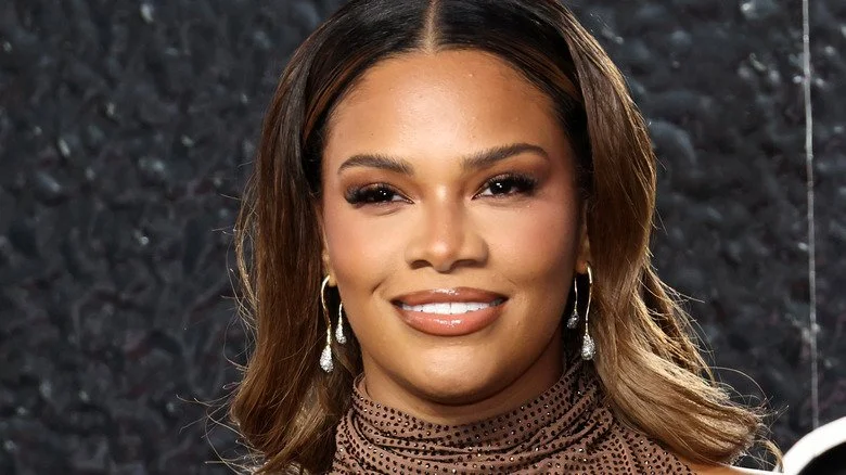 Kamie Crawford souriant dans une robe brune étincelante