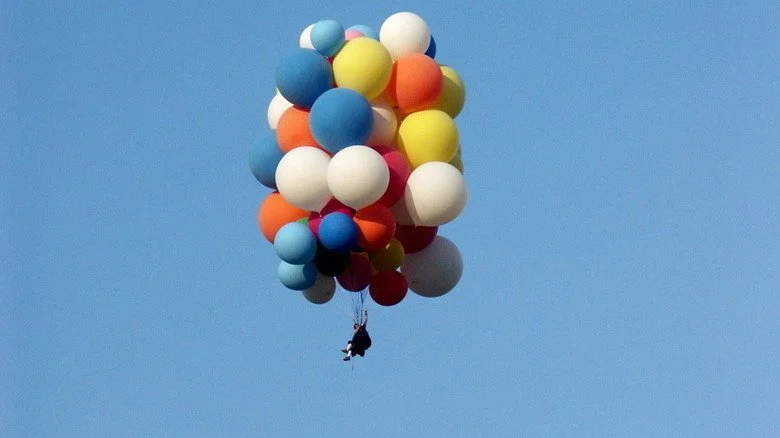 Homme flottant sous des ballons