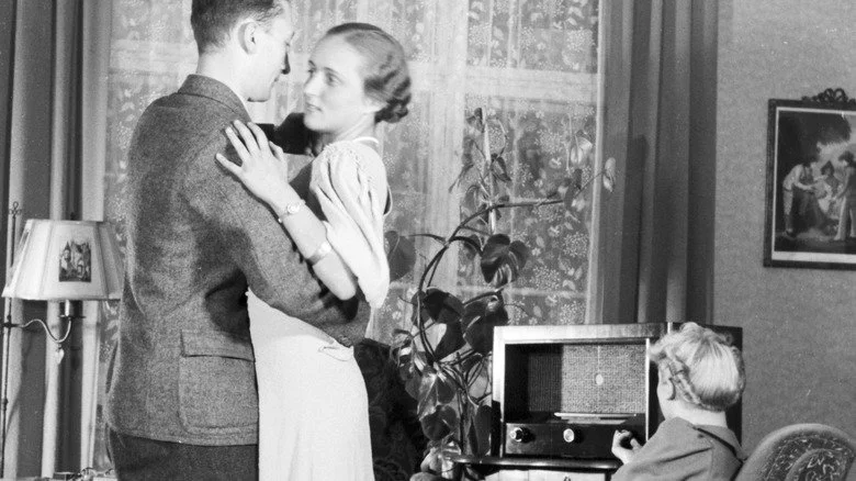 Couple dansant à la maison pendant que la femme tourne le bouton de la radio