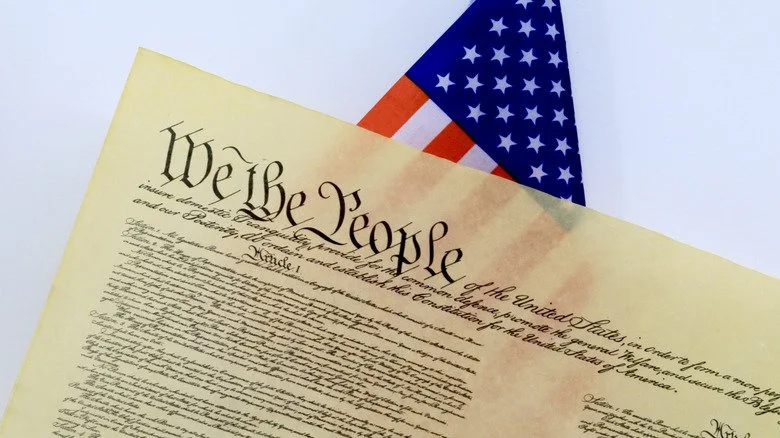 La Constitution des États-Unis devant un drapeau américain