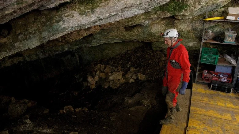Homme en costume rouge excavant une grotte