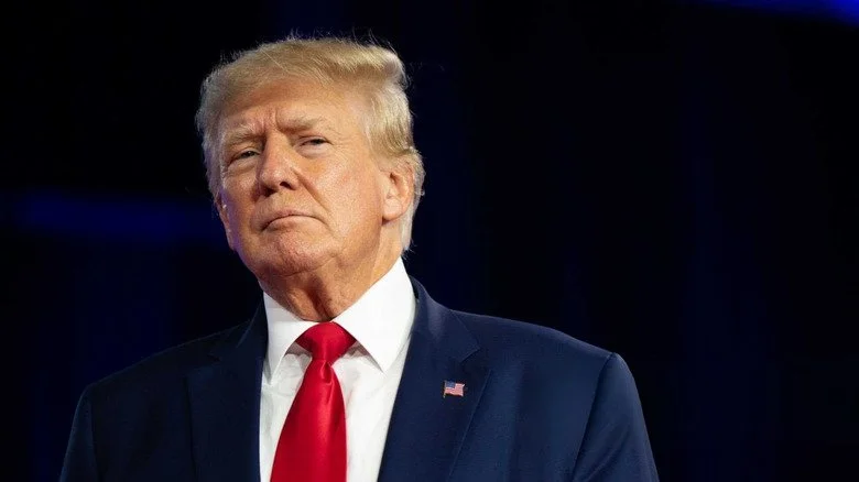 Donald Trump en costume bleu regardant sur le côté, fond noir