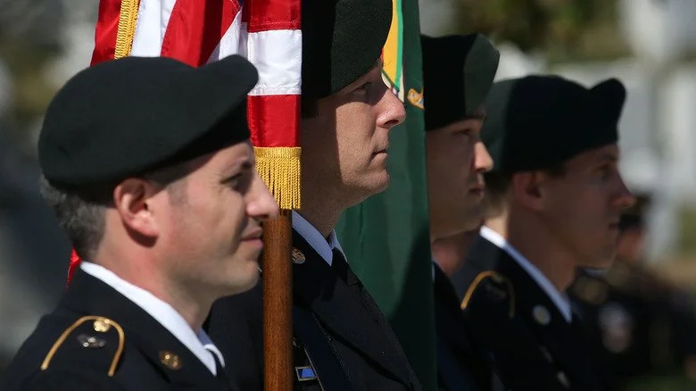 Quatre Green Berets alignés avec des drapeaux