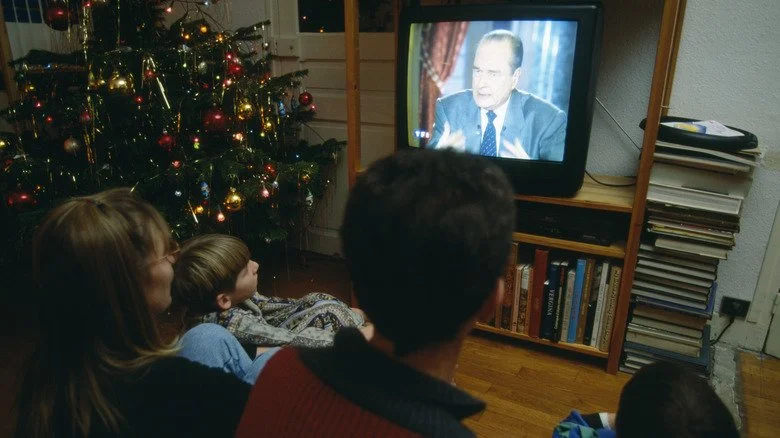 famille regardant la télévision dans les années 90 près du sapin de Noël