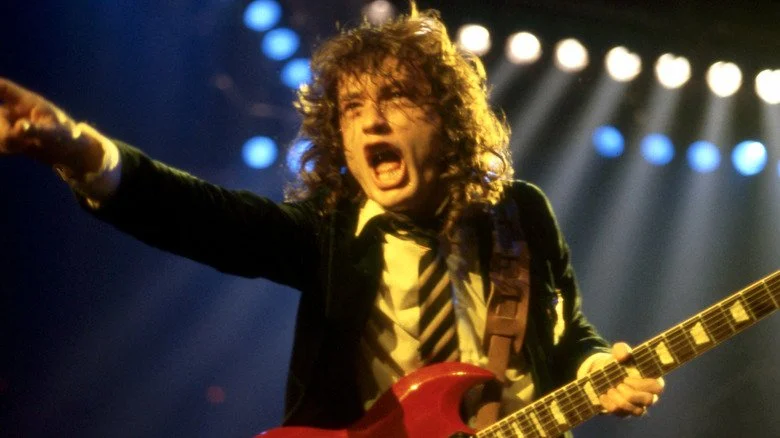 Angus Young screaming and pointing onstage holding guitar