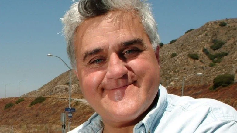 Jay Leno souriant à l'extérieur, portant une chemise en denim